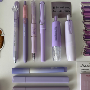 Close-up of the Essential Purple Stationery Bundle featuring pastel pens, highlighters, correction tape, sticky notes, and a notebook