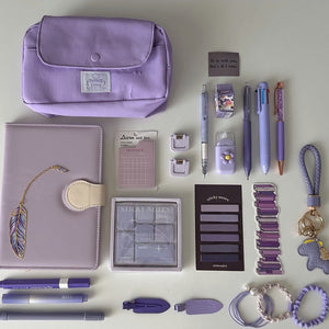 Essential Purple Stationery Bundle flat lay with lavender pencil pouch, notebook, pastel pens, sticky notes, bookmarks, keychain, and hair accessories