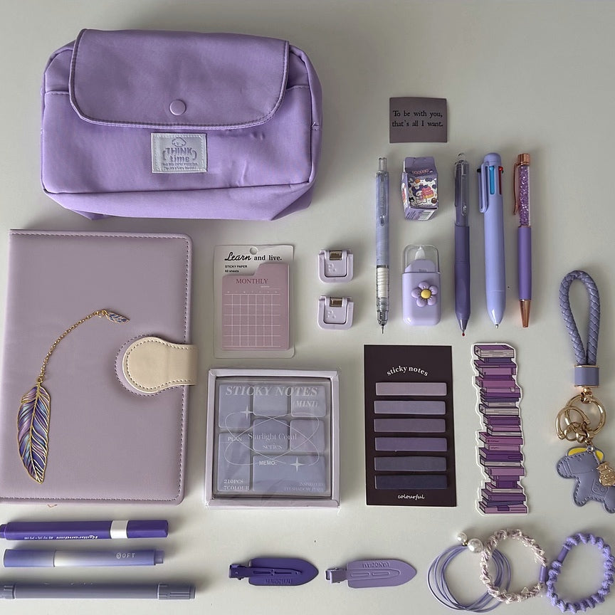 Essential Purple Stationery Bundle flat lay with lavender pencil pouch, notebook, pastel pens, sticky notes, bookmarks, keychain, and hair accessories