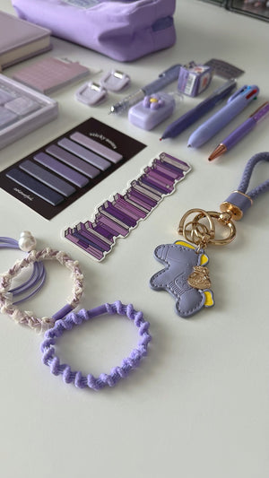 Essential Purple stationery gift box with a lavender pencil pouch, notebook, pastel pens, sticky notes, bookmarks, keychain, and hair accessories