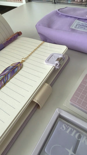 Open notebook with a feather bookmark and planner from the Essential Purple Stationery Gift Box