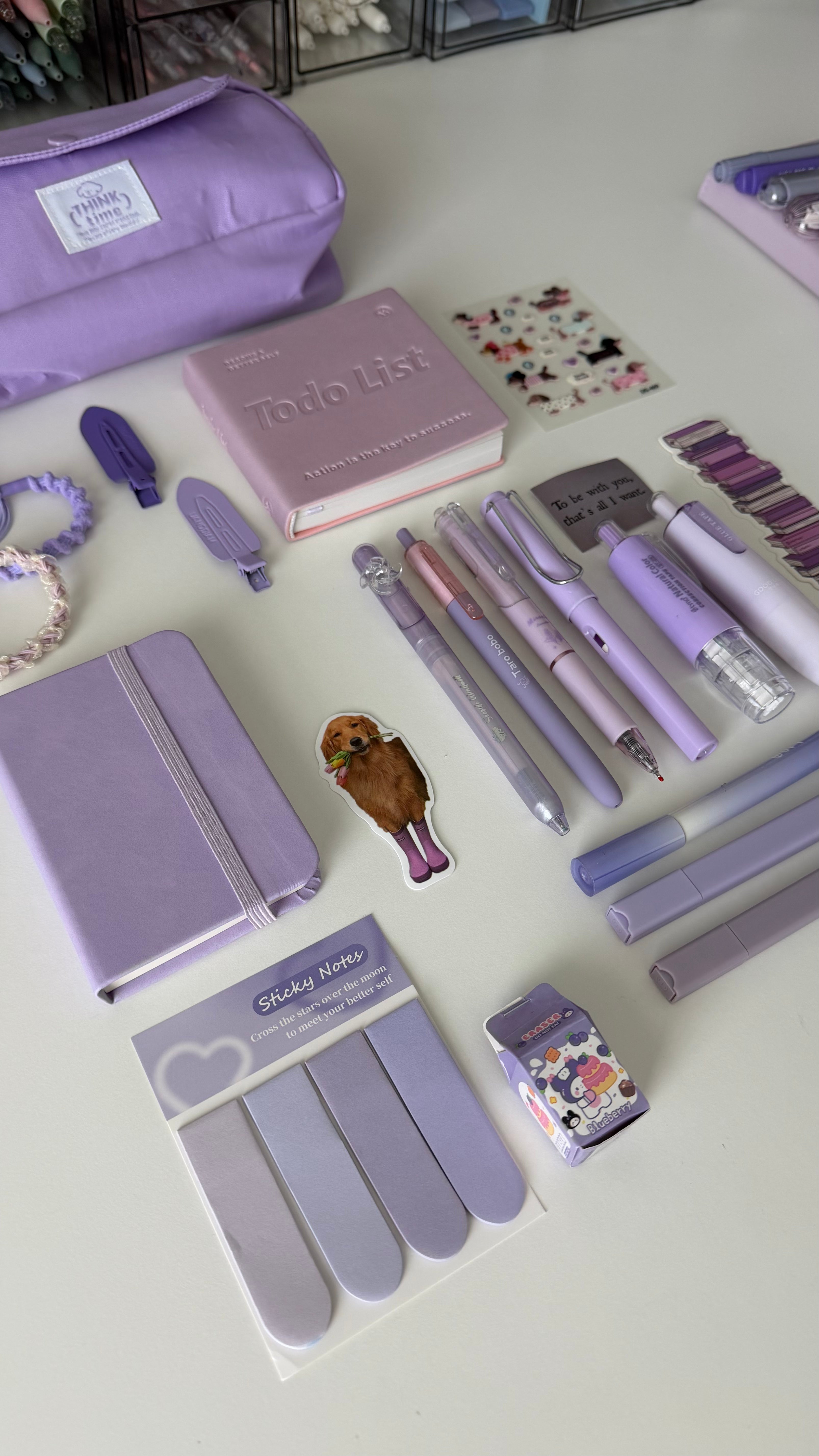 Essential Purple Stationery Bundle featuring a pastel notebook, matching pens, sticky notes, pencil pouch, and accessories