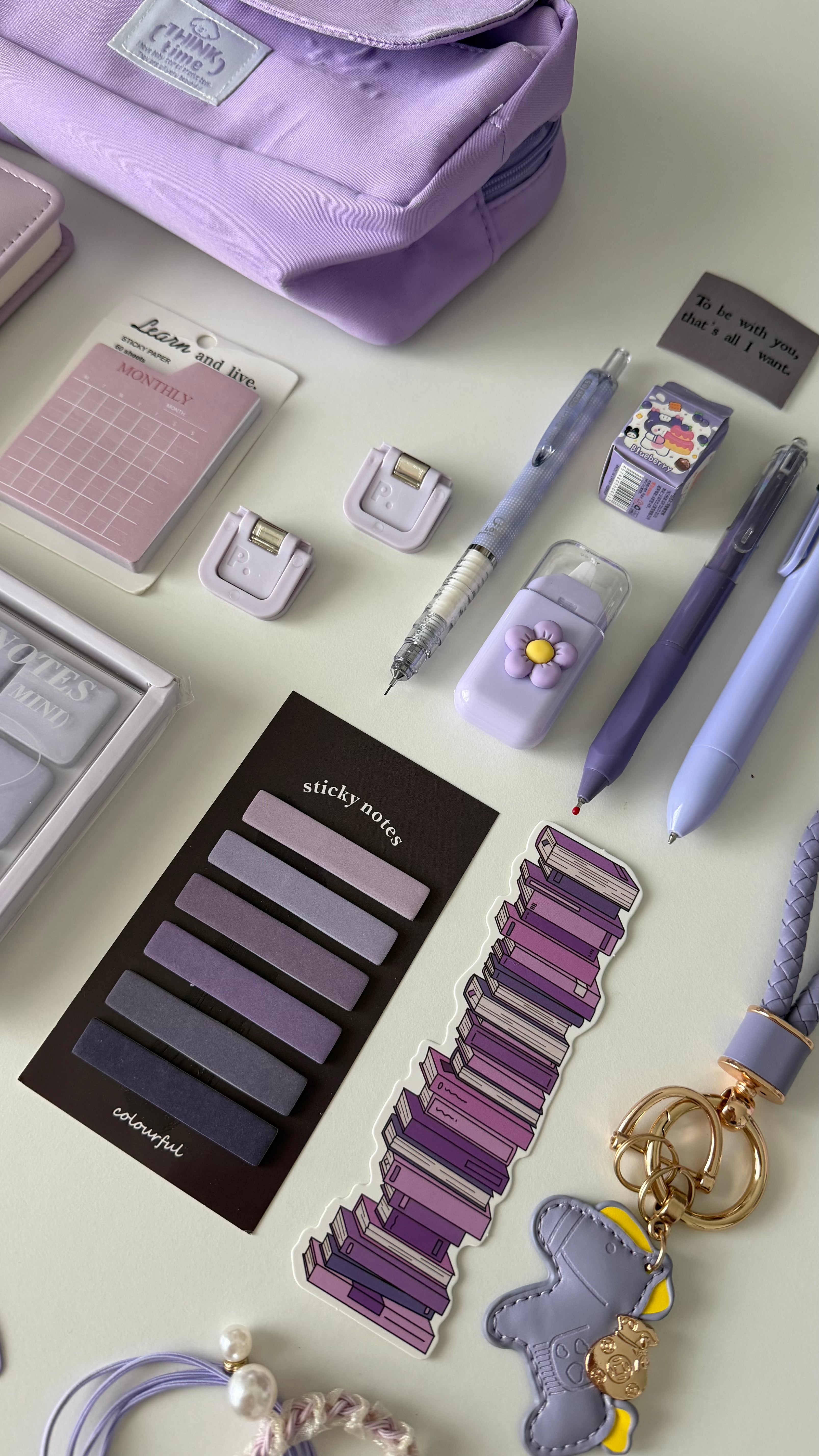 Close-up of stationery accessories from the Essential Purple Stationery Bundle including sticky notes, bookmarks, pens, keychain, and pastel desk essentials