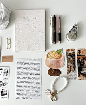 Close-up of the Morning Coffee Stationery Gift Bundle featuring a cream notebook, coffee pens, bookmarks, correction tape, latte memo pad, pearl keychain, and aesthetic stationery.