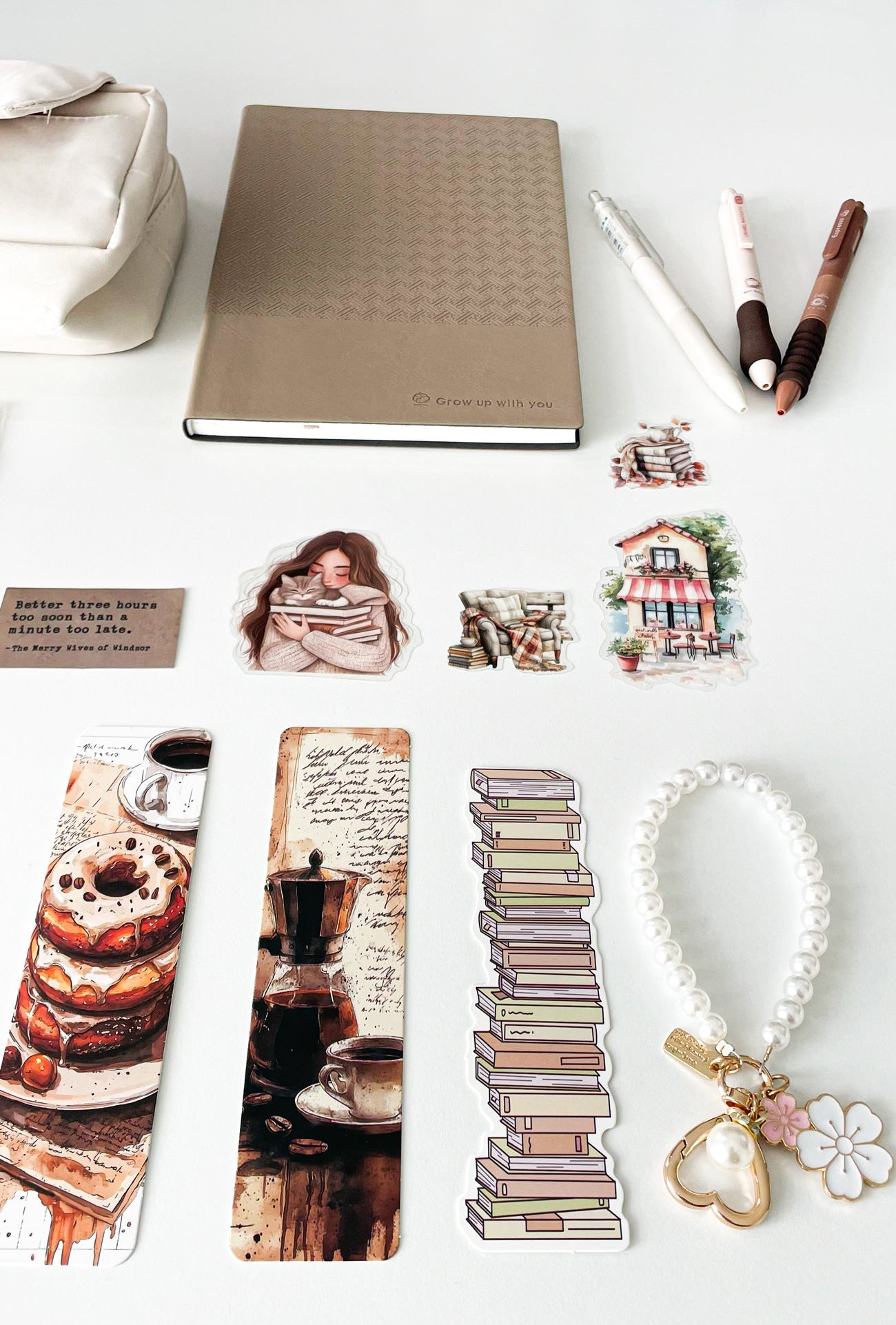 Bookish stationery accessories from the Morning Coffee Stationery Gift Bundle featuring an A5 notebook, coffee-themed bookmarks, cream pens, pearl keychain, decorative stickers and journaling supplies.