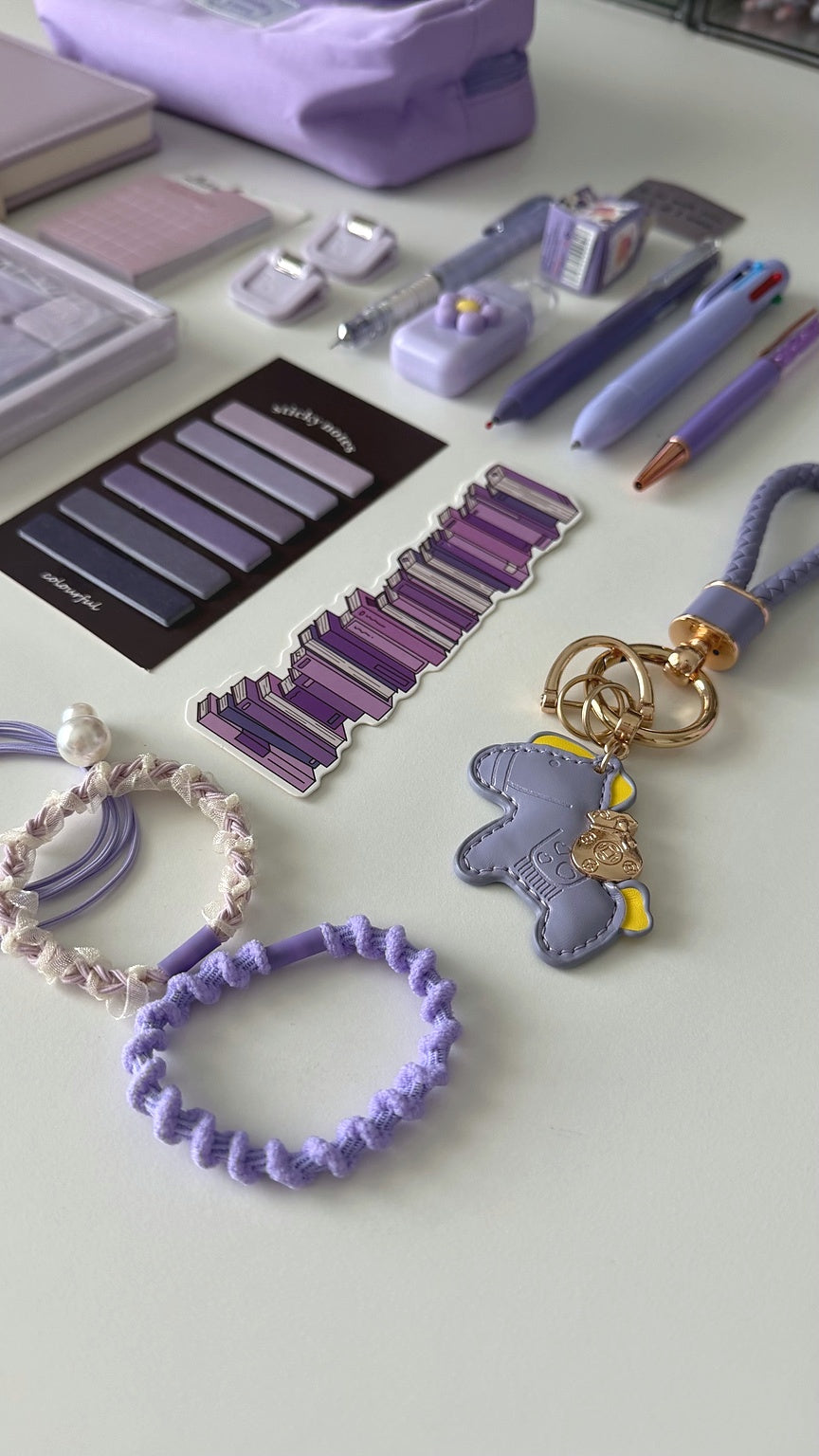 Essential Purple stationery gift box with a lavender pencil pouch, notebook, pastel pens, sticky notes, bookmarks, keychain, and hair accessories