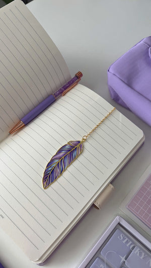 Open notebook with a purple pen and feather bookmark from the Essential Purple Stationery Gift Box
